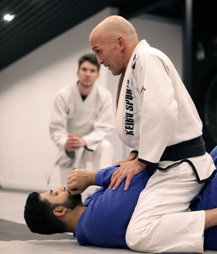 bjj-image-2 BJJ instructor overseeing ground technique training between students.