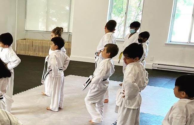 kids-karate-mississauga Children practicing karate stances during class inside the dojo.