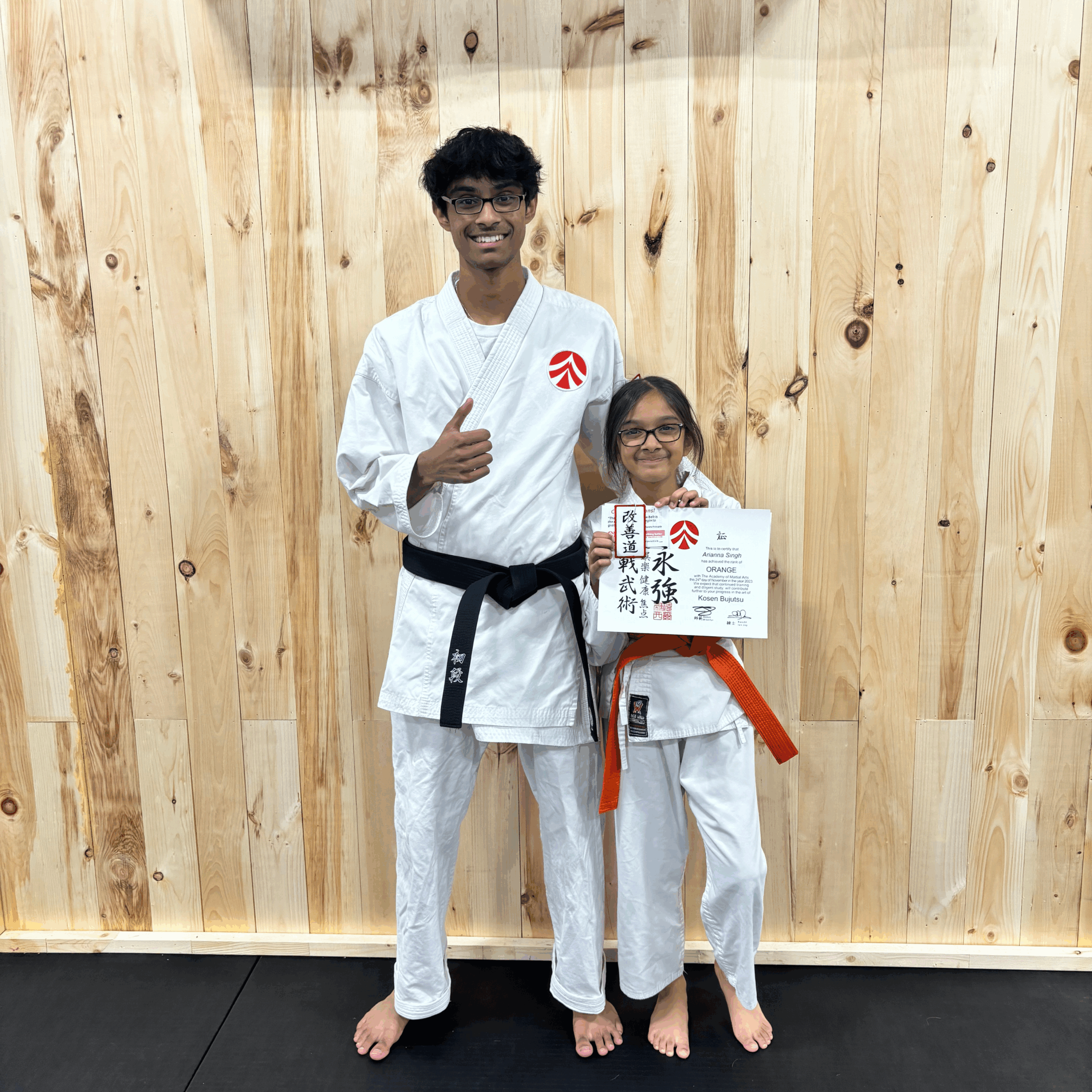 4 Instructor standing beside a young karate student proudly holding a certificate.