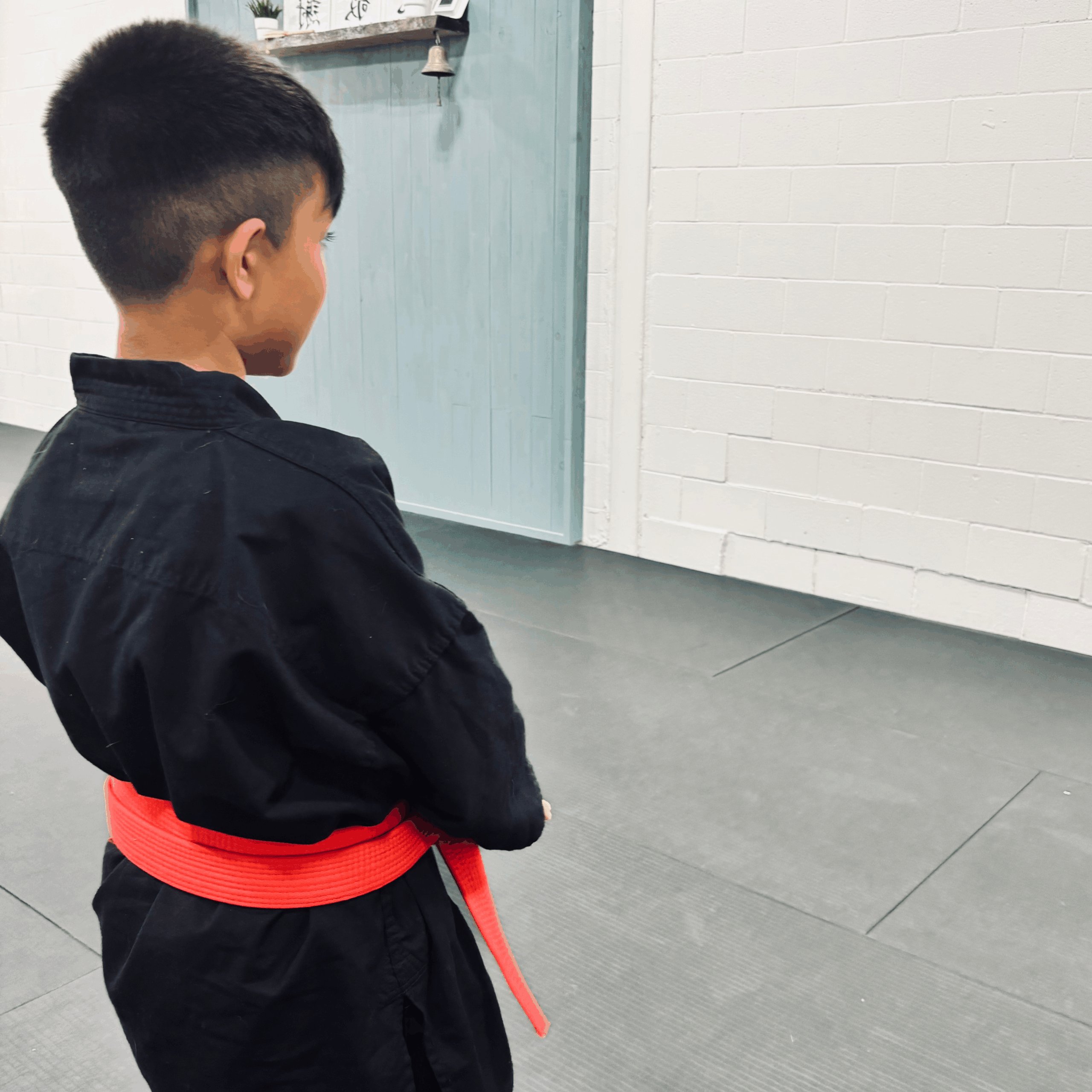 5 Young student in a black gi preparing to begin martial arts training beside classmates.