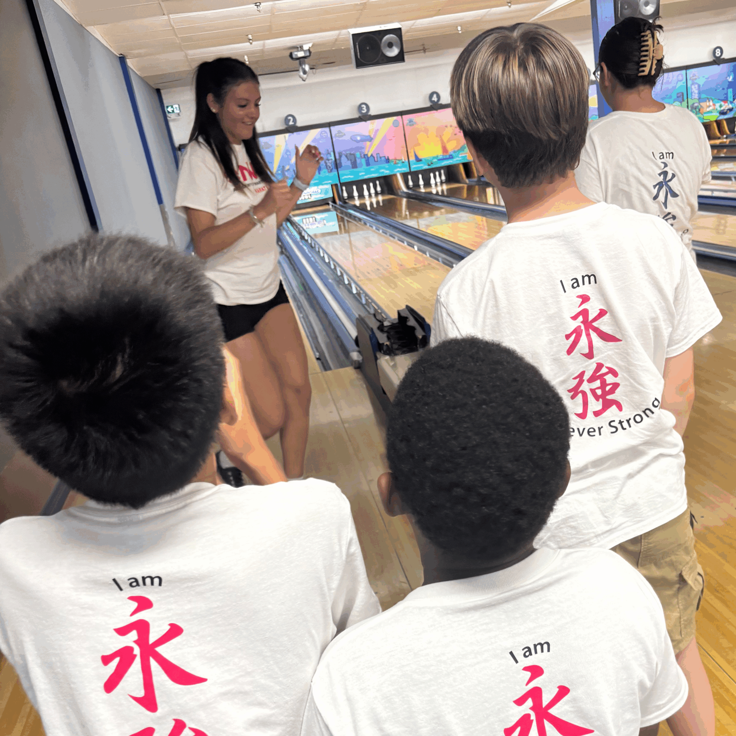 6 Kids bowling while wearing AMA logo t-shirts while on a day trip while attending AMA Karate Camp
